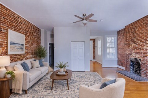 A living room with a brick wall and a fireplace.