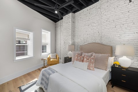 A bedroom with a large bed and a white brick wall.