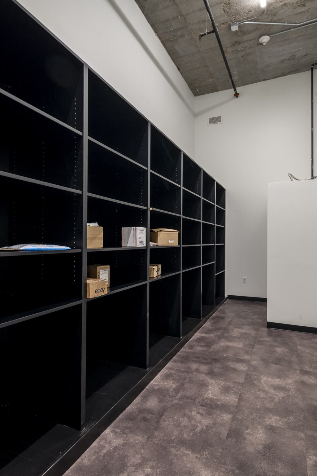 a room with black shelving with boxes on it and a white wall at The Draper, St Louis, MO