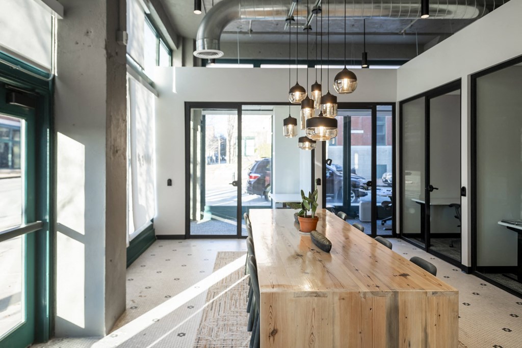 a long wooden table in a lobby with glass doors at The Draper, St Louis, 63103