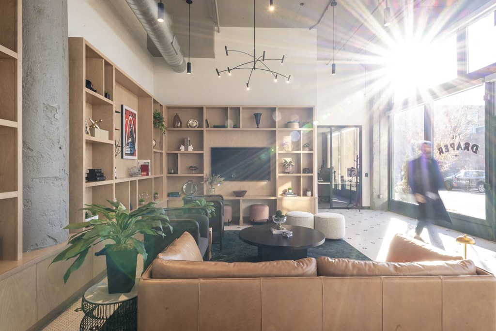 a living room with couches and chairs and a large window at The Draper, St Louis, MO, 63103