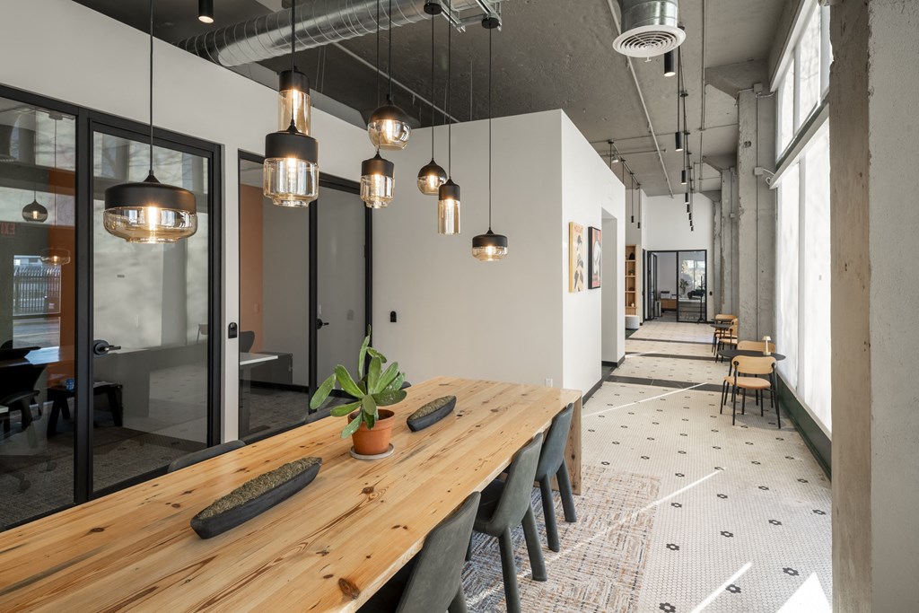 a long wooden table with chairs in a room with large windows at The Draper, St Louis, 63103