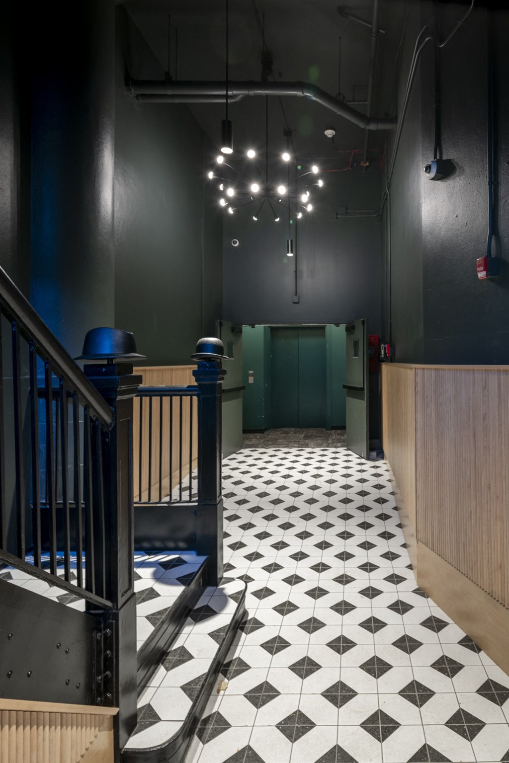 a hallway with a black and white tiled floor and a green door at The Draper, St Louis, MO