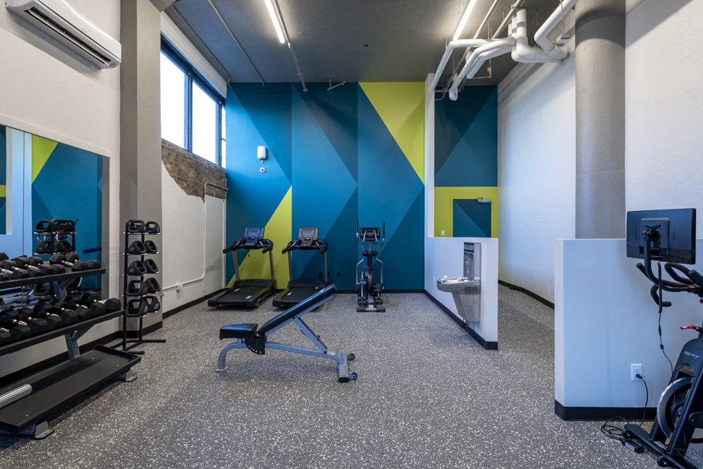 a fitness room with weights and cardio equipment and a blue and yellow wall at The Draper, St Louis, Missouri