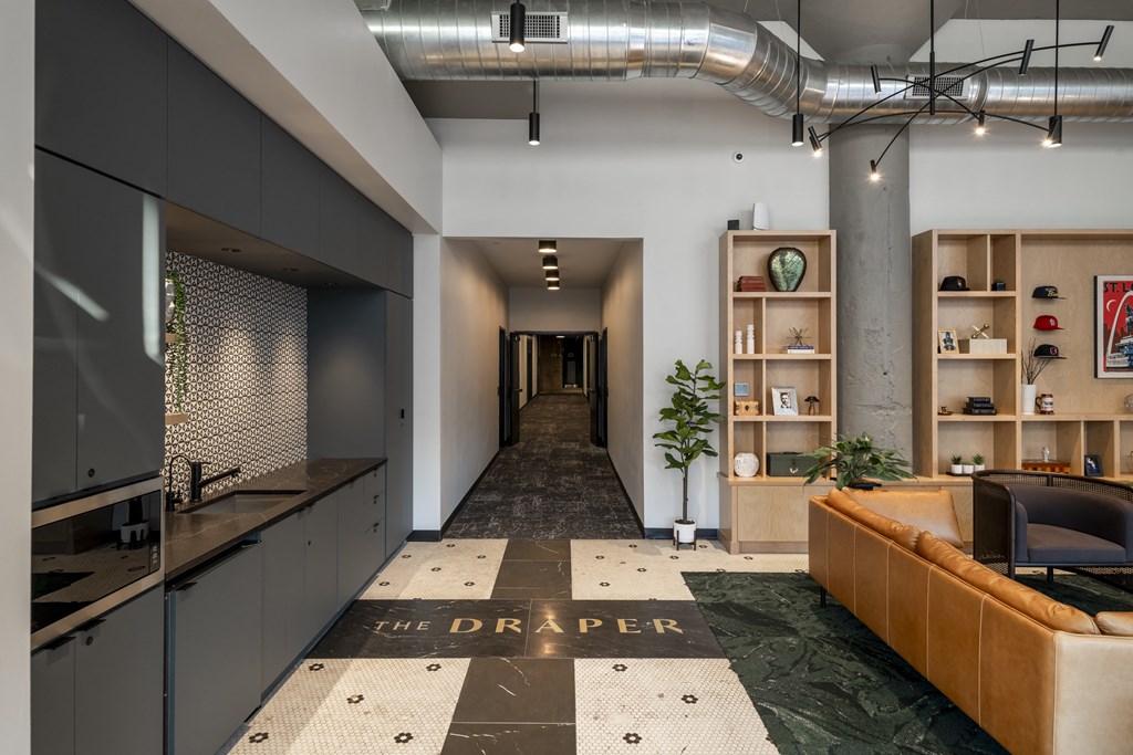 a long hallway with a kitchen and a living room with a couch at The Draper, St Louis, 63103