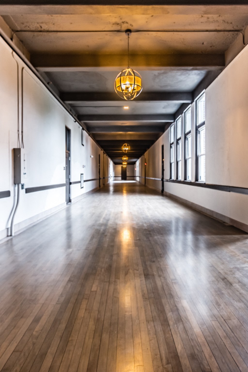 a long empty room with wood floors and a light hanging from the ceiling
