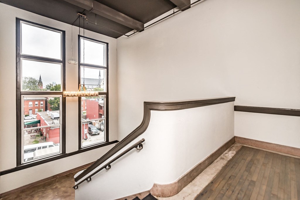 a stairway in a room with a large window and a railing on the wall