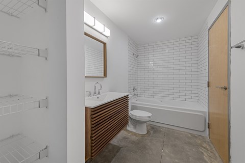 A white tiled bathroom with a toilet, sink, and bathtub.