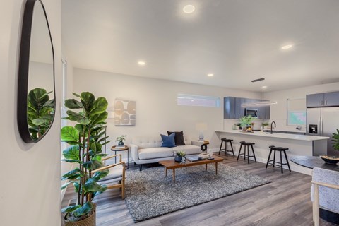 A modern living room with a white couch, a coffee table, and a large mirror on the wall.