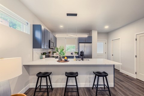 A kitchen with a white countertop and black bar stools.