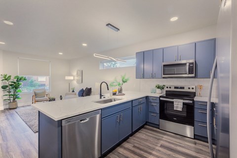 A modern kitchen with blue cabinets and stainless steel appliances.