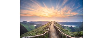 A pathway leading through a mountainous landscape during sunrise or sunset.