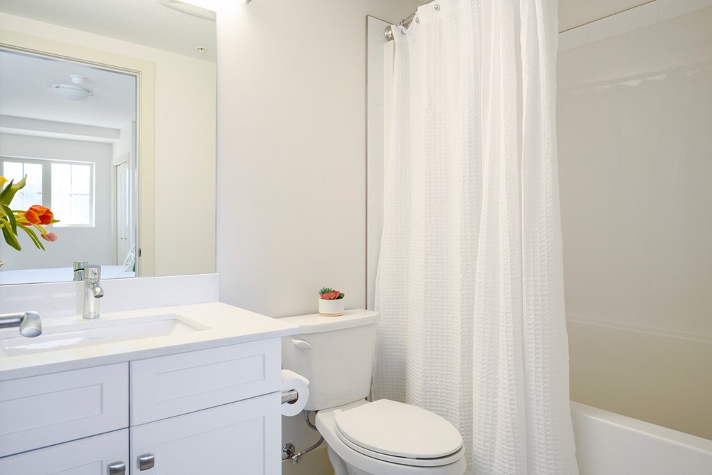 a white bathroom with a white shower curtain and a white sink and toilet
