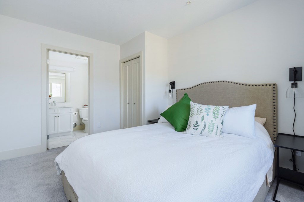 a bedroom with a white bed and a green pillow