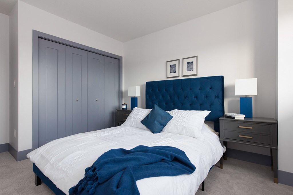 a bedroom with a large bed and a blue tufted headboard