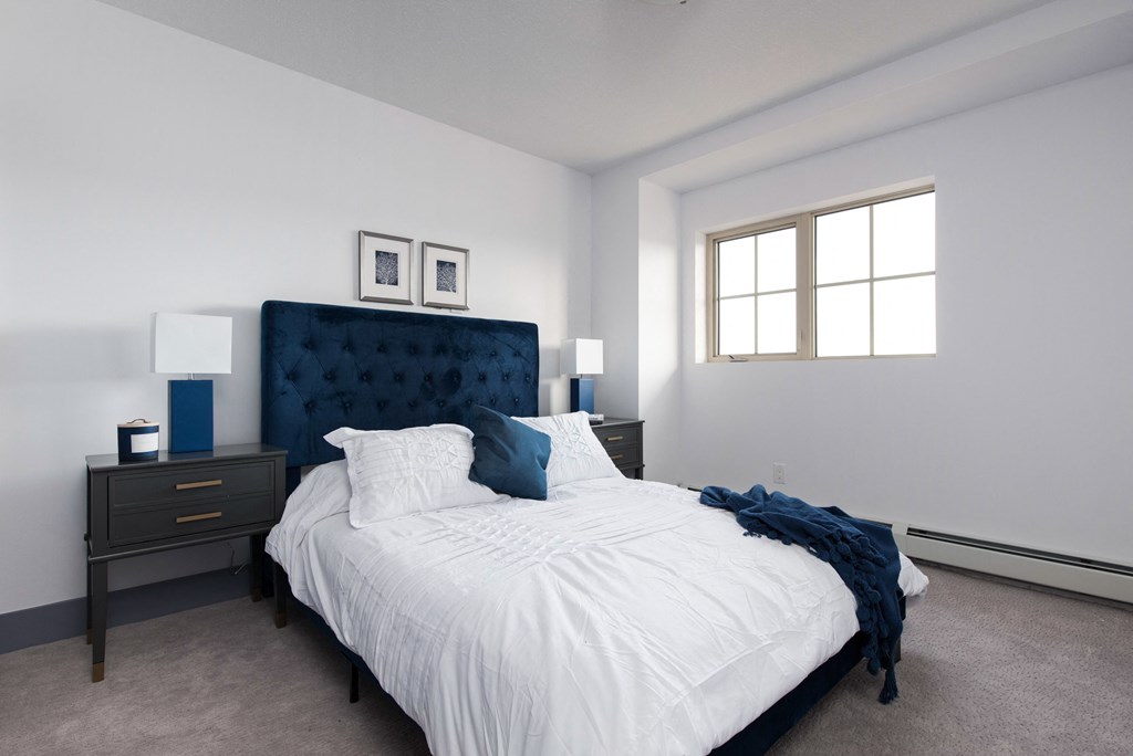 a bedroom with a bed and two nightstands and a window