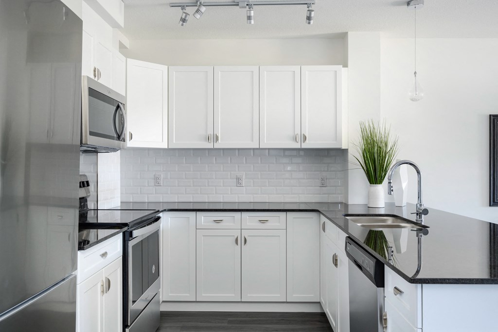 a kitchen with white cabinets and a black counter top