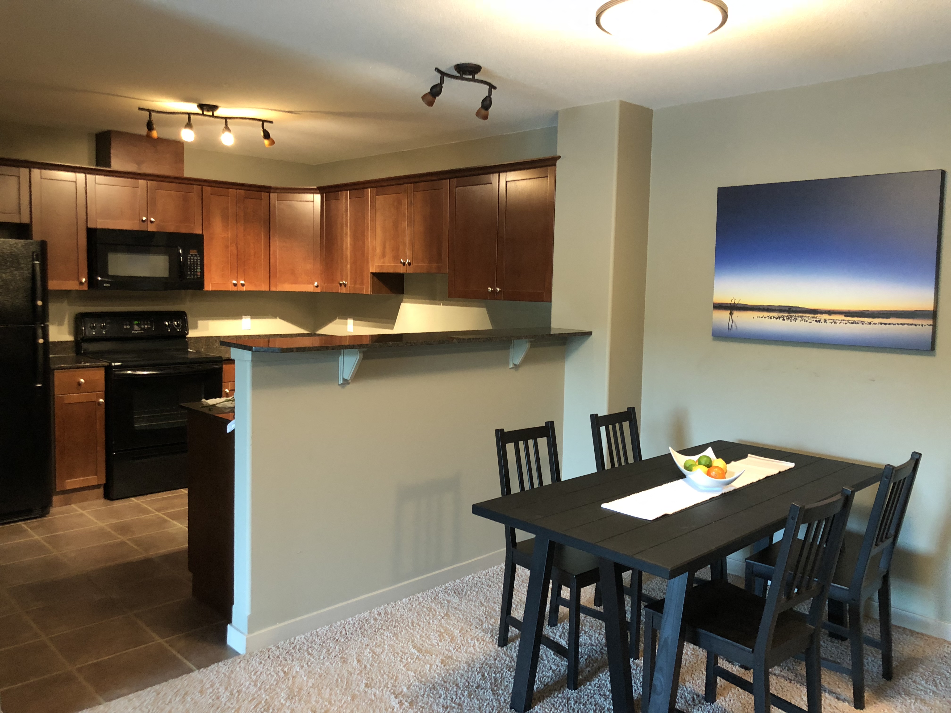 A modern kitchen with a dining table set for two.