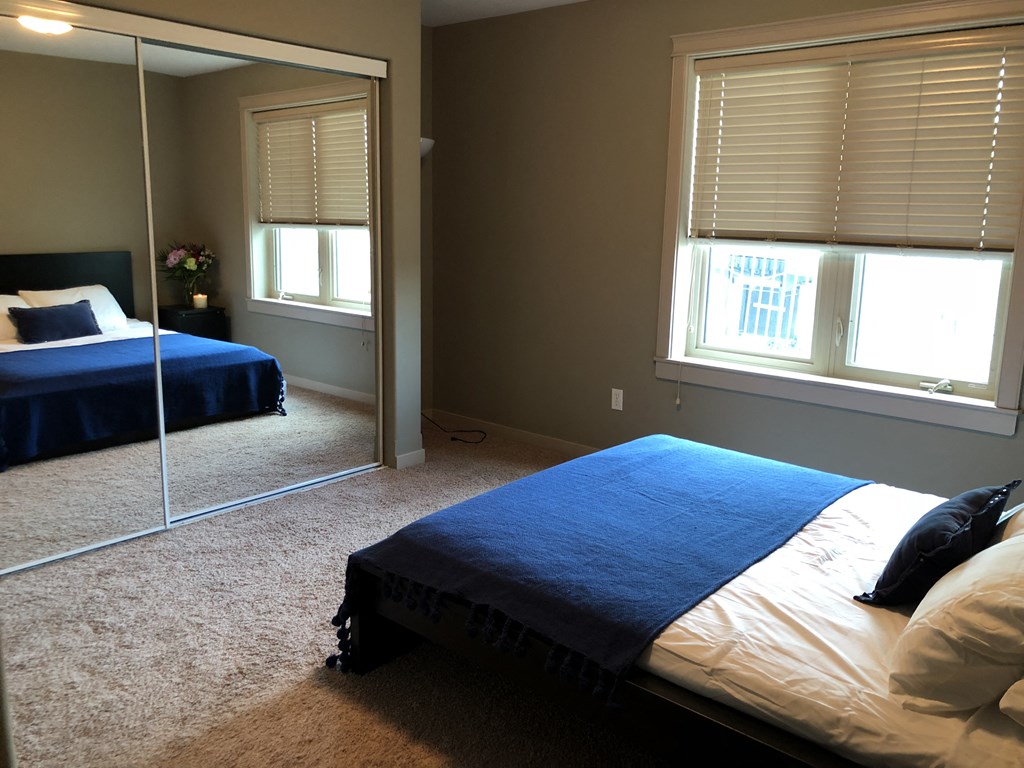 A bedroom with a bed and a mirror.