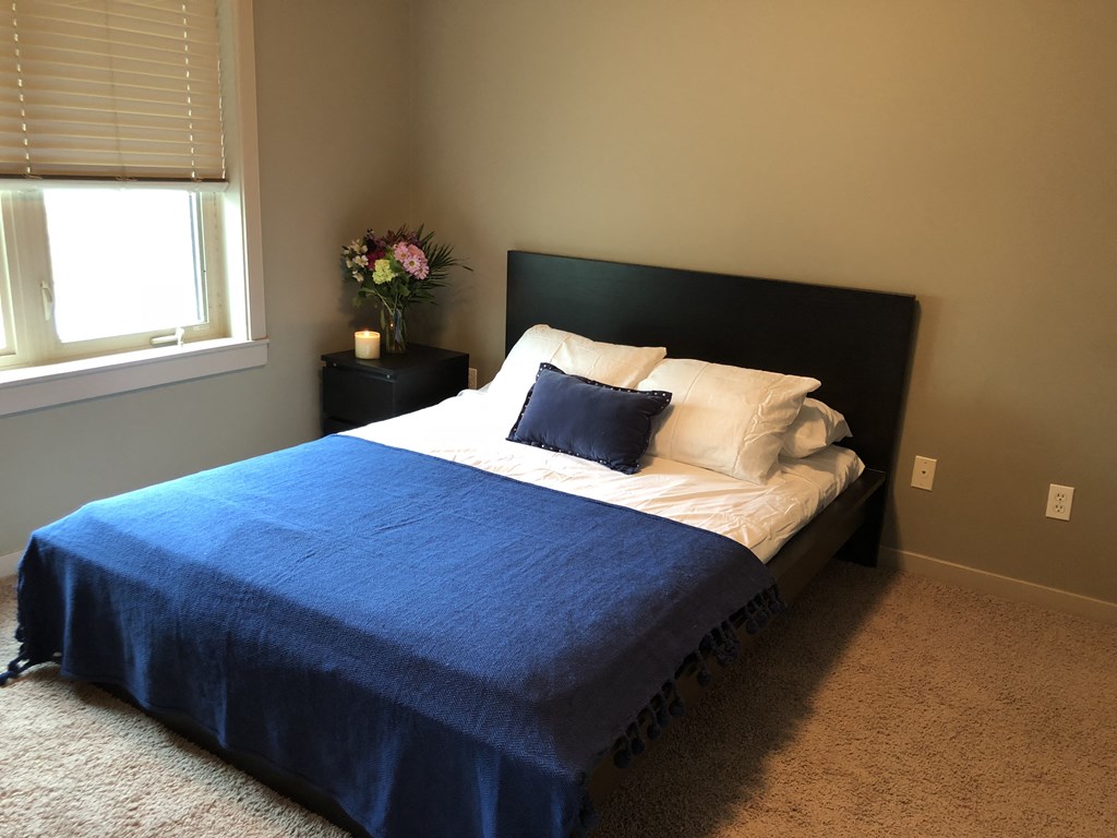 A bed with a blue cover and white pillows in a room.