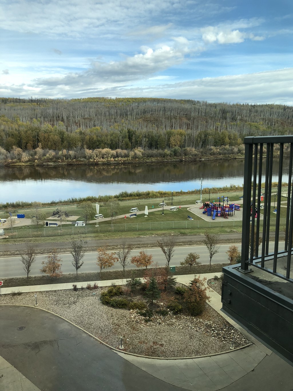 A view from a balcony overlooking a lake and a parking lot.