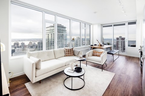 A white couch sits in a living room with a view of the city.