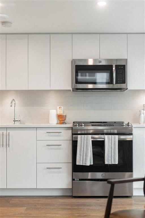 a kitchen with white cabinets and a stove and a microwave