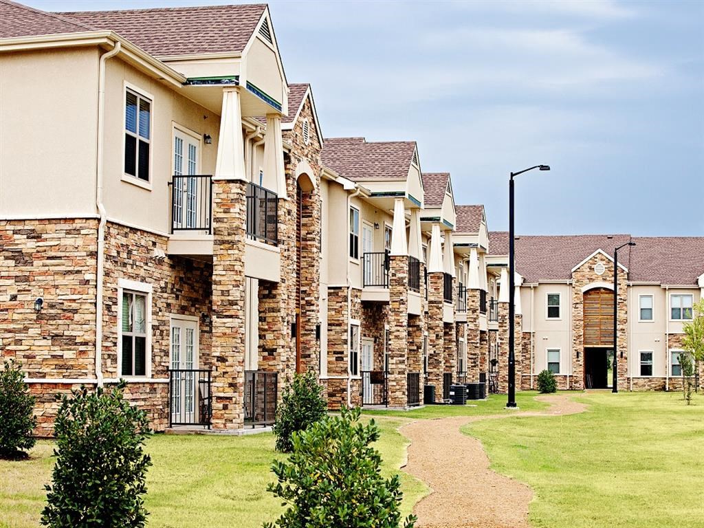 a row of brick apartment buildings with grass and trees