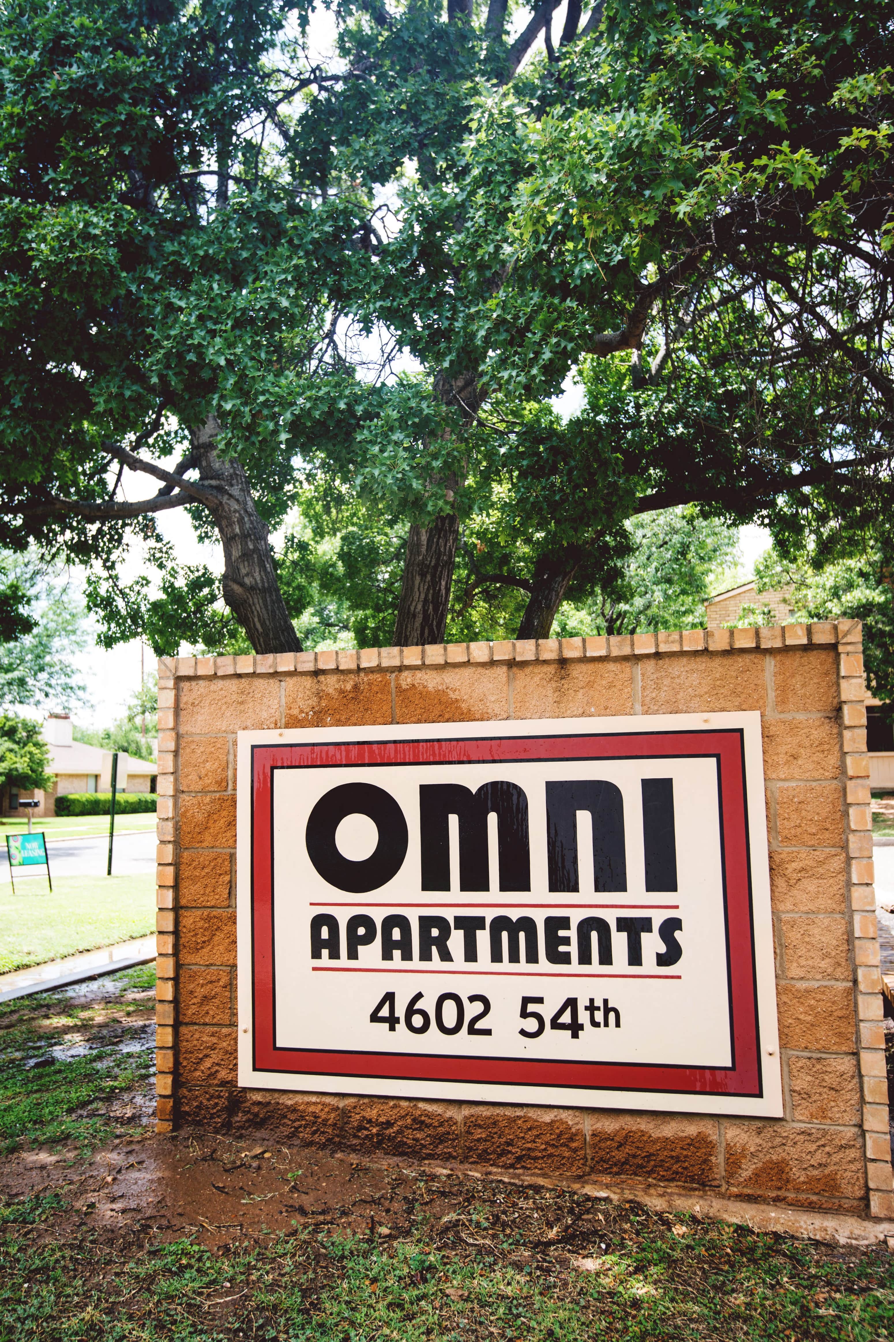 a sign for omni apartments in front of a tree