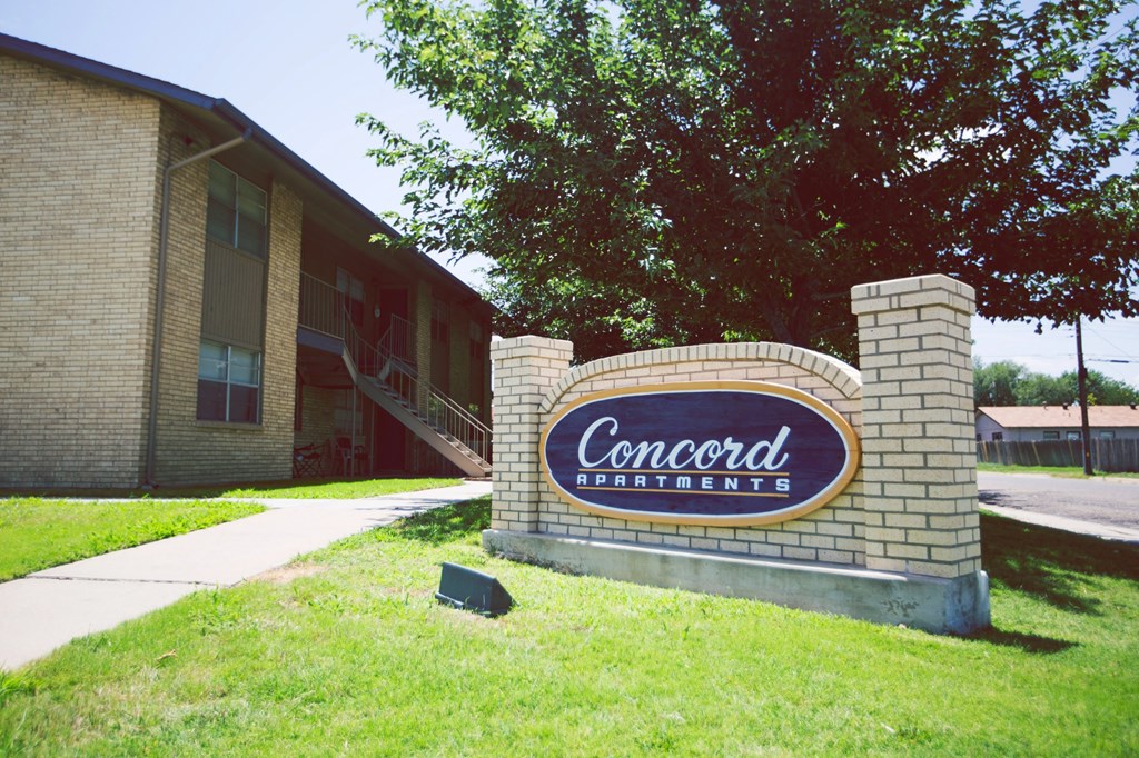 a sign for concord apartments in front of a brick building