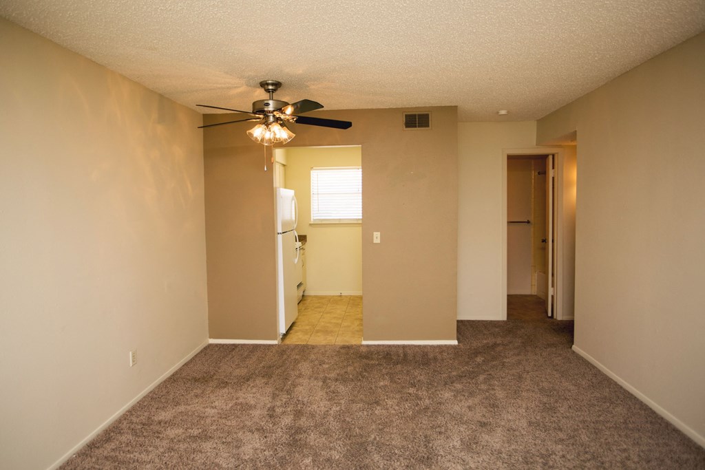 an empty living room with carpet and a ceiling fan