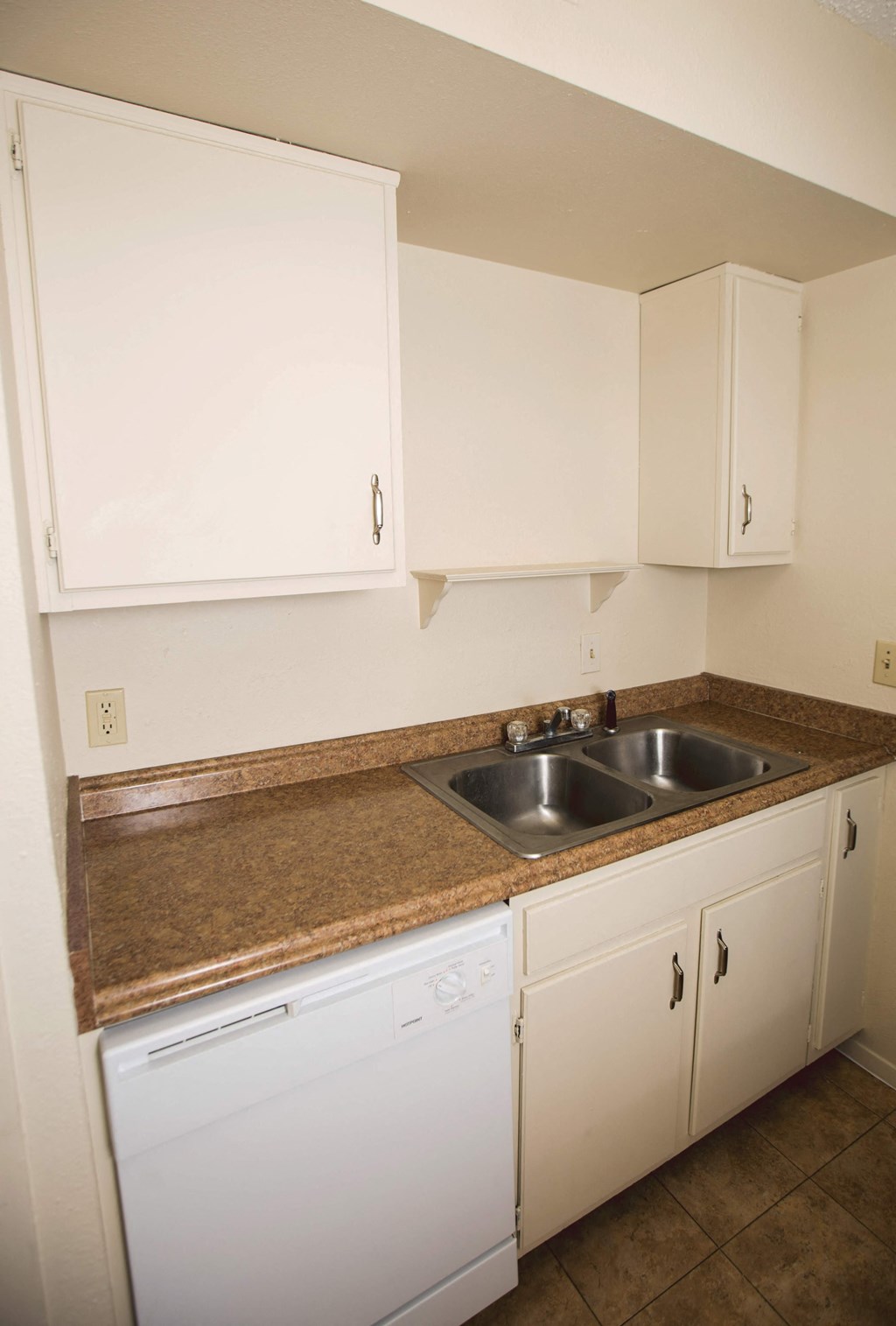 an empty kitchen with white cabinets and a sink