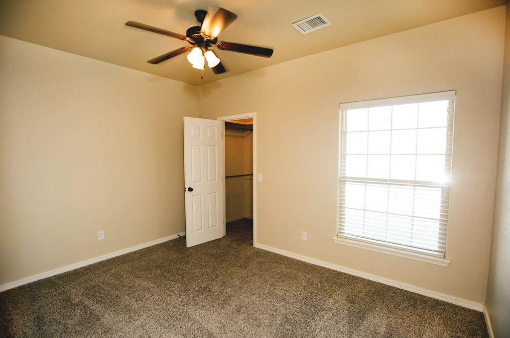 a bedroom with a ceiling fan and a door to a closet