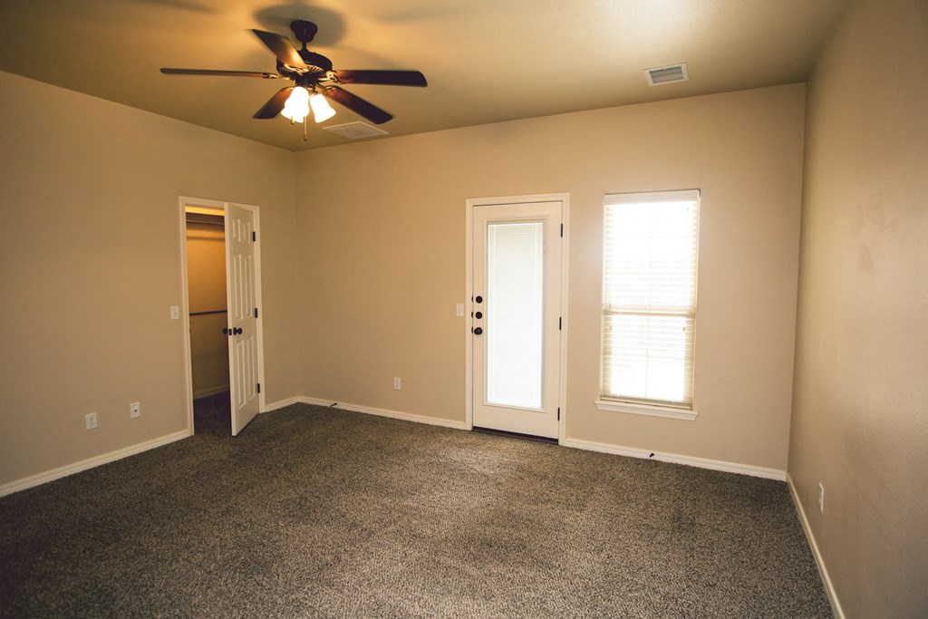 an empty living room with a ceiling fan and doors