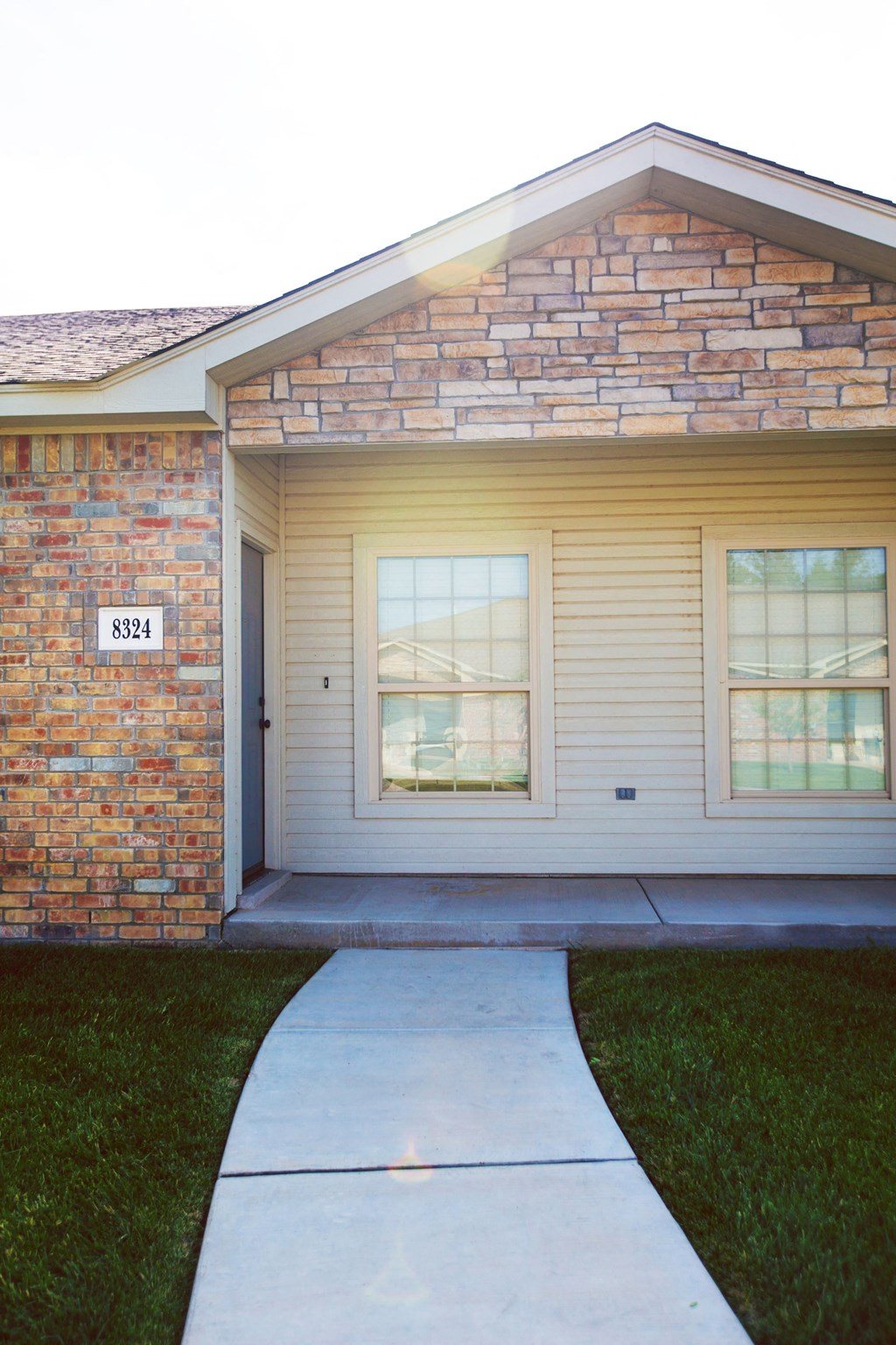 the front of a brick house with a sidewalk in front of it