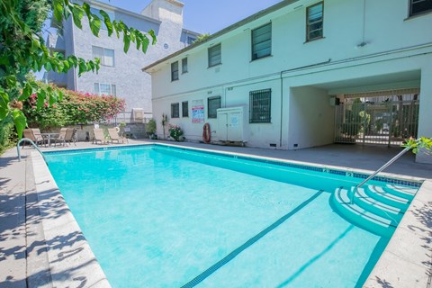 A swimming pool in front of a white building.