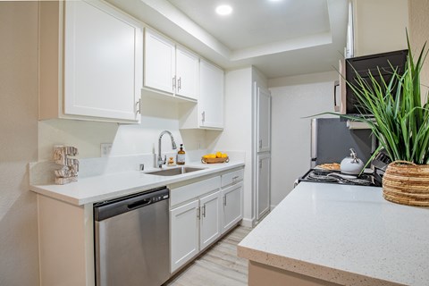 a kitchen with white cabinets and a white counter top and a sink