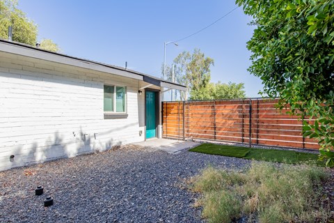 a small white house with a blue door and a wooden fence