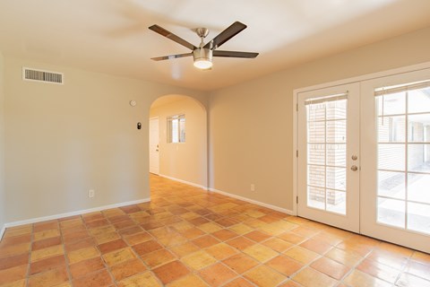 an empty living room with a ceiling fan and french doors