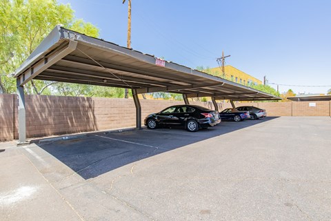 a parking lot with three cars under a metal awning