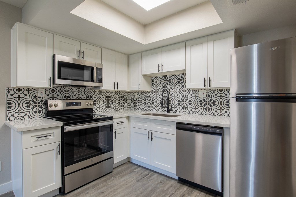 a kitchen with white cabinets and stainless steel appliances