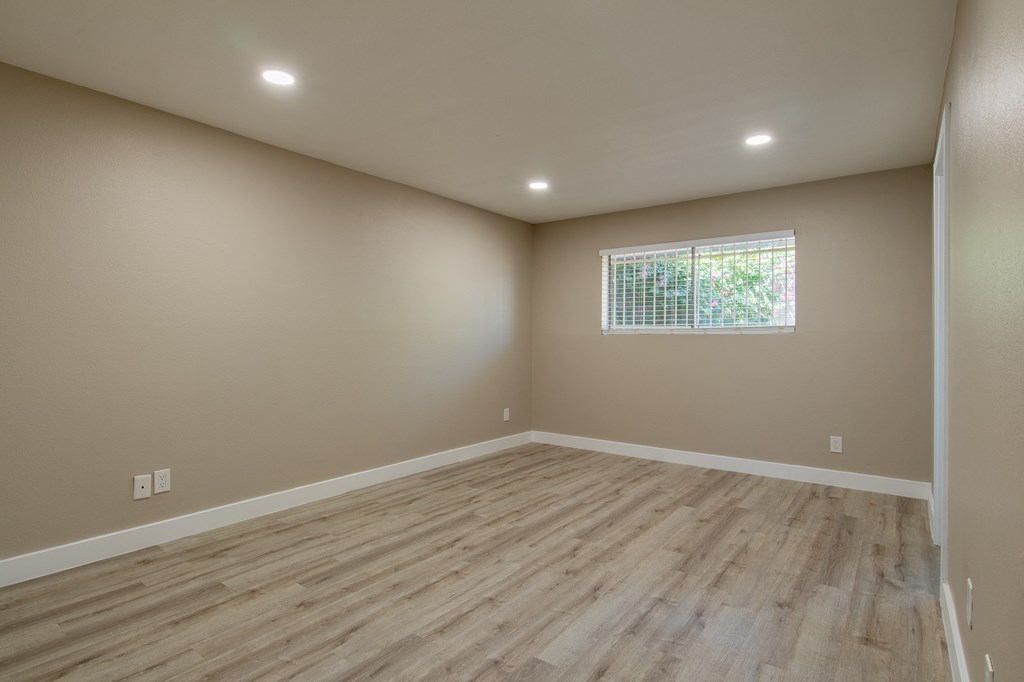 a bedroom with hardwood floors and beige walls