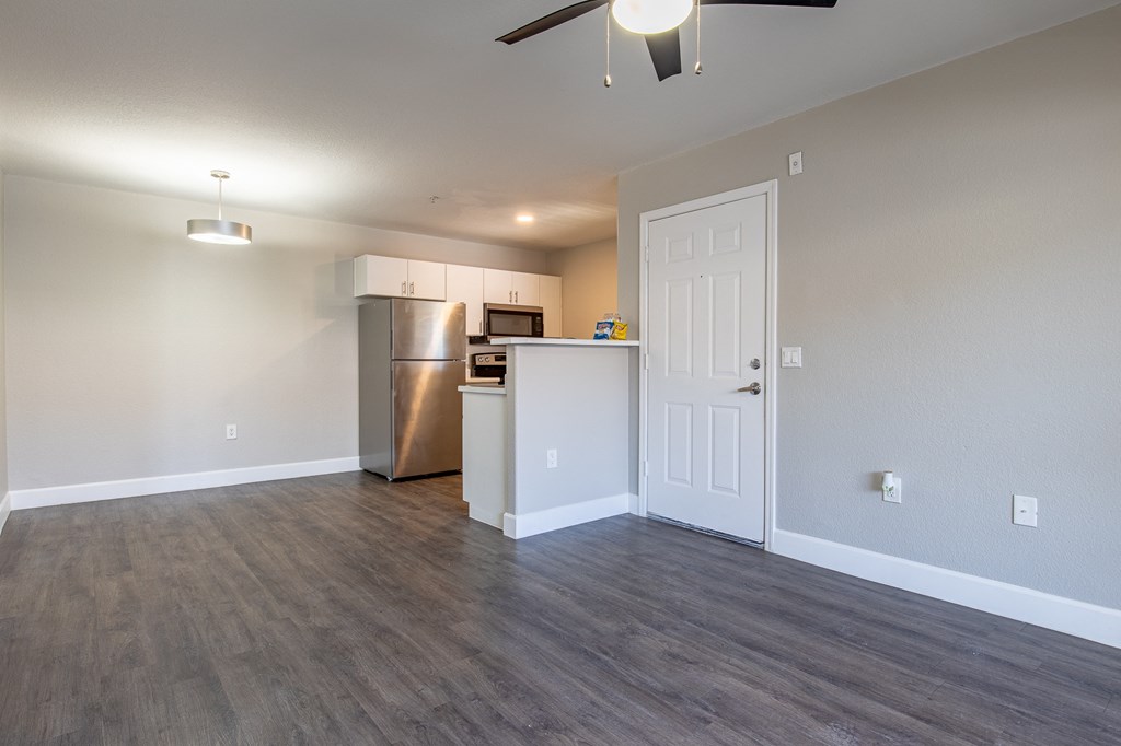 a living room with a ceiling fan and a kitchen in the background
