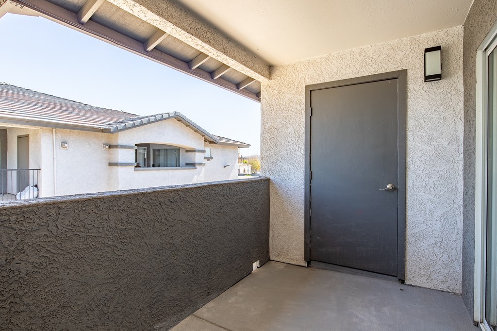 the front door of a home with a black door and a balcony