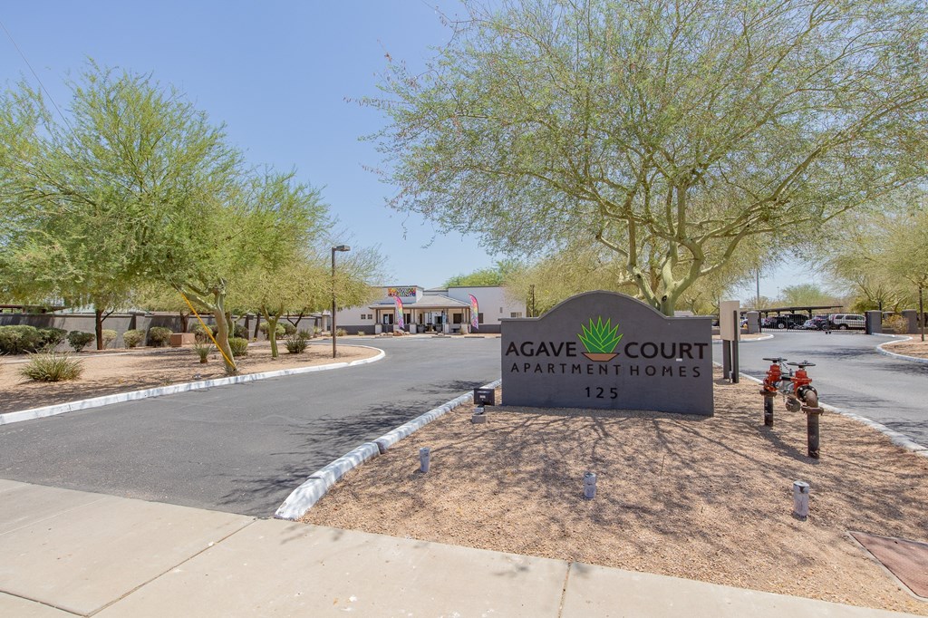 a sign that says agave court apartments with a building in the background
