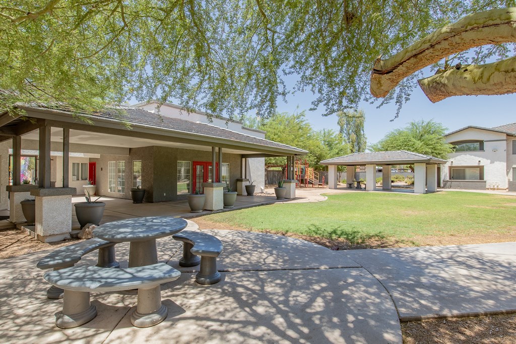 a patio with a table and benches in front of a building