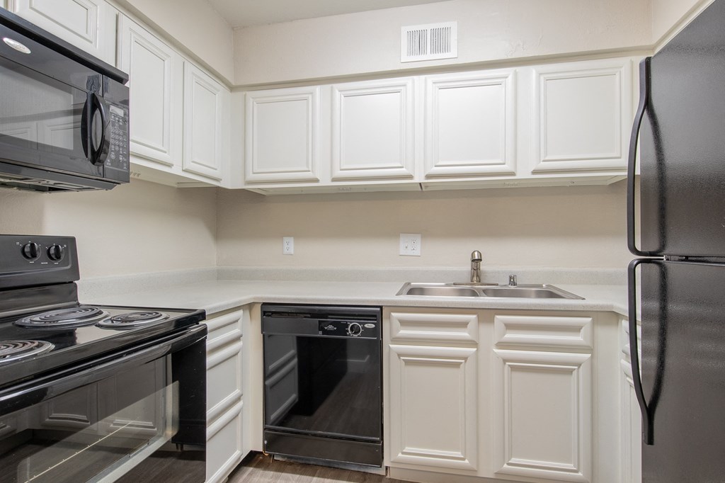 a kitchen with white cabinets and black appliances