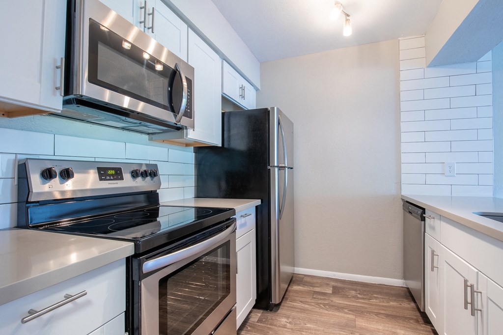 a kitchen with white cabinets and stainless steel appliances