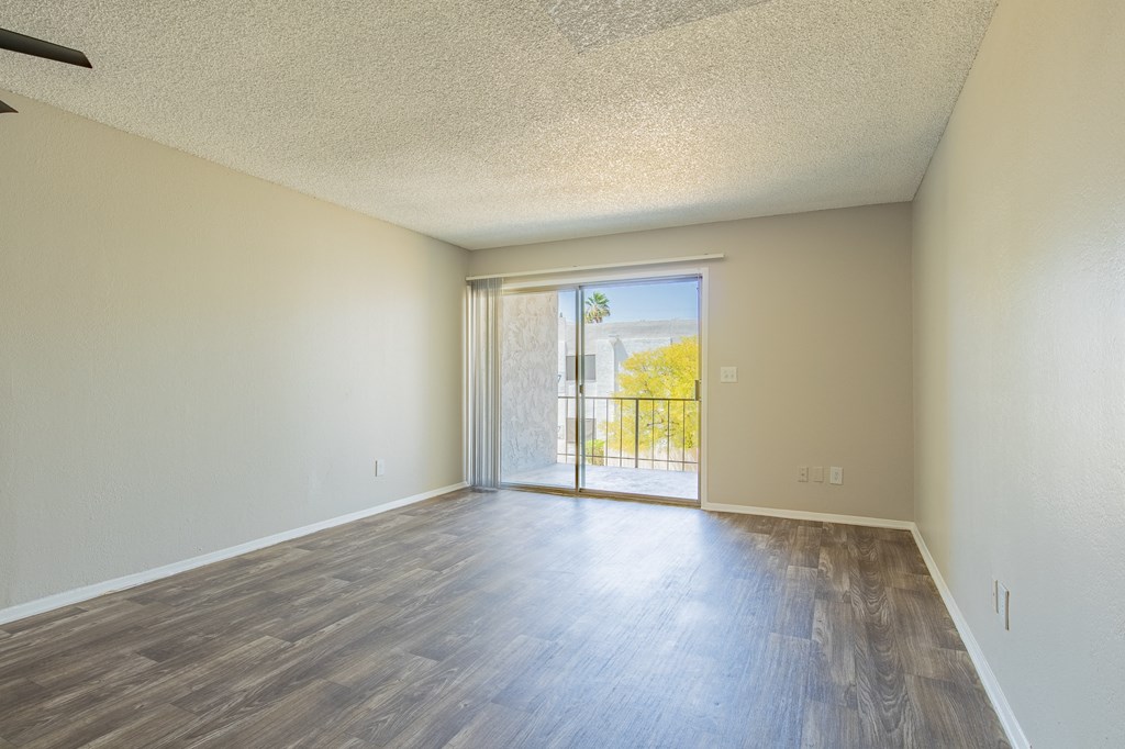 a bedroom with hardwood flooring and a sliding glass door leading to a balcony