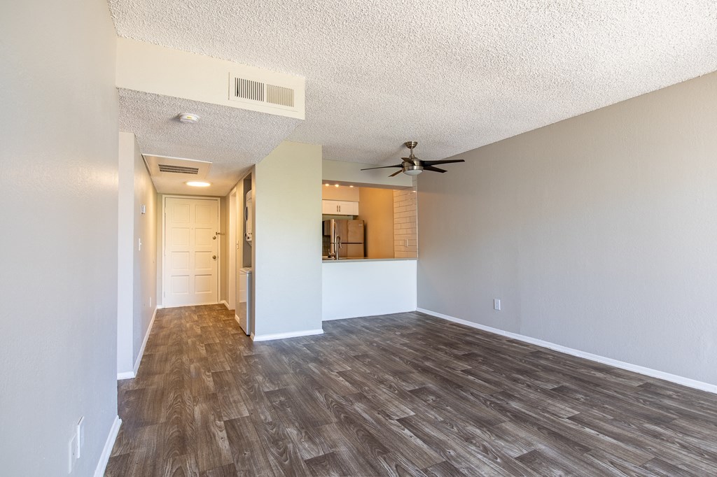 an empty living room with a ceiling fan